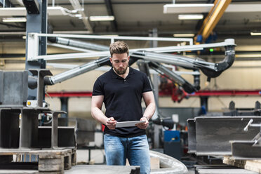 Mann mit Tablet in einer Fabrikhalle stehend - DIGF03550