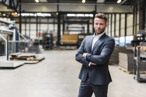 Portrait of confident businessman standing on factory shop floor stock photo