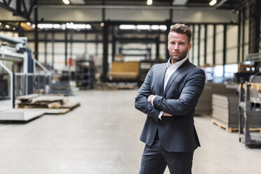 Portrait of confident businessman standing on factory shop floor - DIGF03556