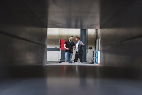 Zwei Männer mit Klemmbrett unterhalten sich in einer Fabrikhalle - DIGF03557