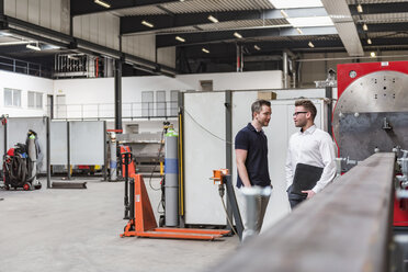 Zwei Männer stehen und sprechen in einer Fabrikhalle - DIGF03576