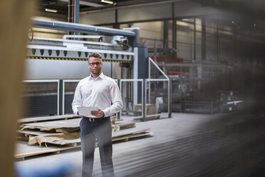 Businessman using tablet on factory shop floor - DIGF03584