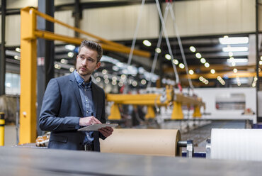 Businessman using tablet on factory shop floor - DIGF03599