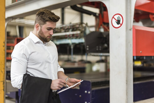 Mann benutzt Tablet in einer Fabrikhalle - DIGF03604