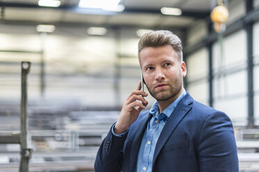 Portrait of confident businessman on cell phone in factory - DIGF03633