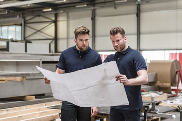 Zwei Männer betrachten einen Plan in einer Fabrik - DIGF03649