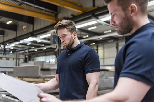 Zwei Männer betrachten einen Plan in einer Fabrik - DIGF03650