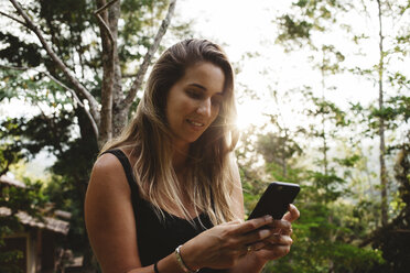 Frau benutzt Smartphone im Hof - CAVF31377