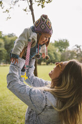 Happy mother lifting daughter while playing at park - CAVF31393