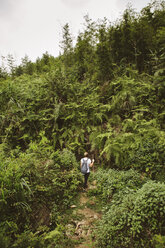 Hohe Winkel Ansicht der Frau mit Rucksack Wandern auf Feld inmitten von Pflanzen - CAVF31397