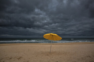 Sonnenschirm auf Sand am Meer gegen Sturmwolken - CAVF31435