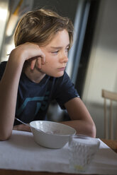 Junge sitzt am Tisch mit Schüssel und Glas - FOLF05815