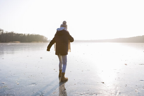 Deutschland, Brandenburg, Straussee, Rückenansicht eines Mädchens, das auf einem zugefrorenen See spazieren geht - OJF00249