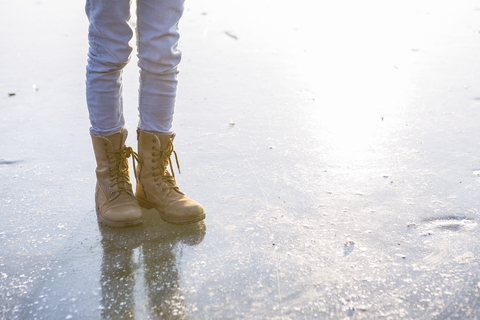 Deutschland, Brandenburg, Straussee, Füße mit Stiefeln auf zugefrorenem See, lizenzfreies Stockfoto