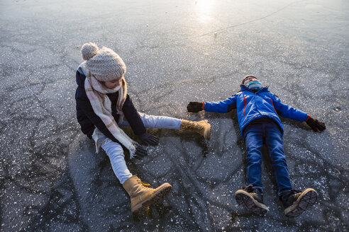 Deutschland, Brandenburg, Straussee, zwei Kinder sitzen und liegen auf dem zugefrorenen See - OJF00254