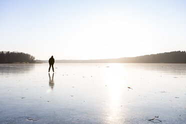 Deutschland, Brandenburg, Straussee, zugefrorener See und Silhouette eines Schlittschuhläufers - OJF00255