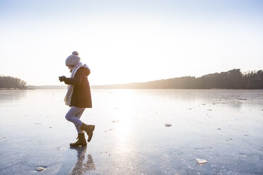 Germany, Brandenburg, Lake Straussee, girl walking on frozen lake - OJF00256