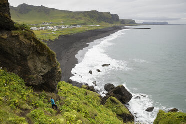 Hiker looking from cliff at black sand beach in Iceland - FOLF05868