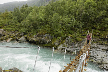 Man walking on suspension bridge over river at Jotunheimen - FOLF05902