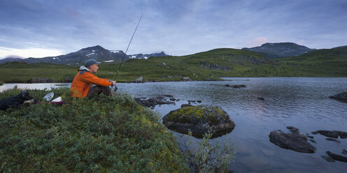 Man fishing in lake Sjuendevatnet at dusk - FOLF05920