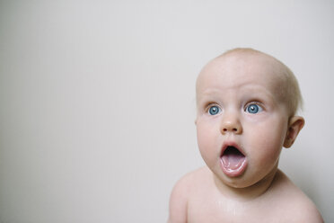 Cute baby girl with mouth open against wall - CAVF31645