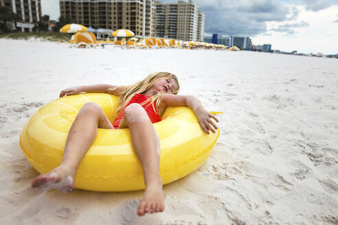 Mädchen in voller Länge, das sich auf einem Schlauch am Strand entspannt - CAVF31707