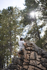 Rückansicht eines Wanderers, der eine Felsformation gegen Bäume im Wald erklimmt - CAVF31729