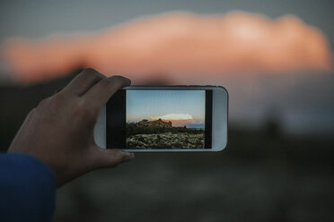 Abgeschnittene Hand einer Frau, die mit ihrem Smartphone eine Landschaft fotografiert - CAVF31769