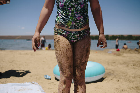 Mittelteil eines Mädchens in Badekleidung auf Sand am Strand stehend - CAVF31845