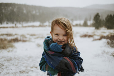 Porträt eines glücklichen, in eine Decke eingewickelten Mädchens im Winter - CAVF31852