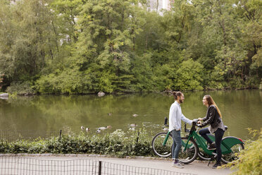 Hohe Winkel Ansicht der glücklichen Paar im Gespräch, während stehend mit Fahrrädern am See - CAVF31875