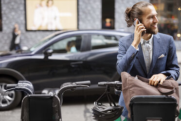 Geschäftsmann, der auf einem Parkplatz steht und mit seinem Handy telefoniert - CAVF31888