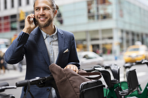 Geschäftsmann, der auf einem Parkplatz in der Stadt steht und mit seinem Handy telefoniert, lizenzfreies Stockfoto