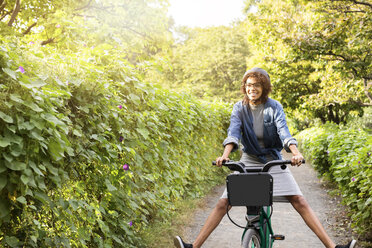 Glückliche Frau fährt Fahrrad im Park - CAVF31912