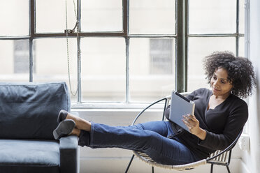 Businesswoman using digital tablet while resting on chair at office - CAVF31954