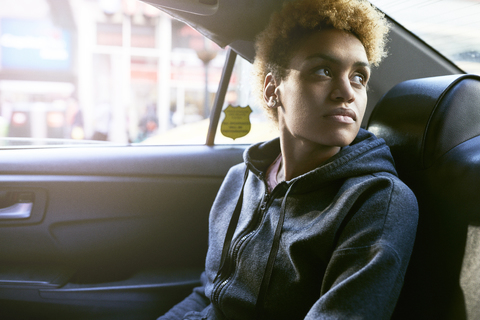 Nachdenkliche junge Frau sitzt im Taxi, lizenzfreies Stockfoto