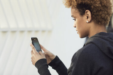 Side view of young woman using smart phone in city during sunny day - CAVF31994