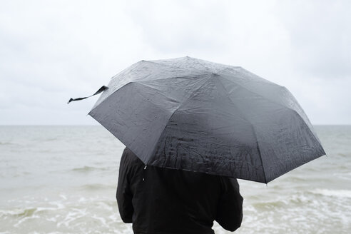 Frau unter schwarzem Regenschirm beobachtet die Ostsee - FOLF06014