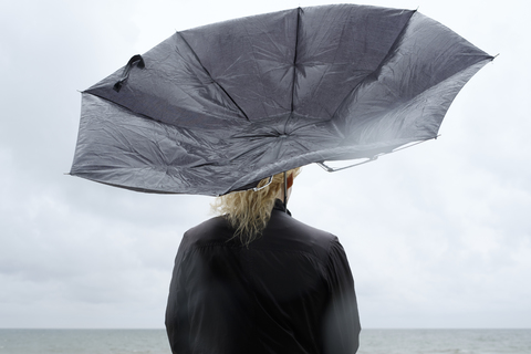 Woman under black umbrella watching Baltic Sea stock photo