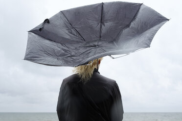 Woman under black umbrella watching Baltic Sea - FOLF06016