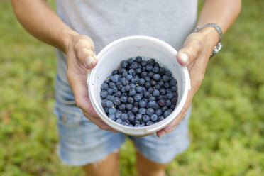 Mittelteil einer reifen Frau, die einen Eimer mit Blaubeeren hält - FOLF06027