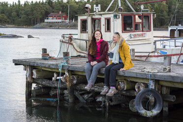 Jugendliches Mädchen sitzt mit junger Frau auf dem Bootssteg - FOLF06039