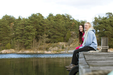 Jugendliches Mädchen sitzt mit junger Frau auf dem Bootssteg - FOLF06040