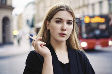 Portrait of young woman smoking in street - FOLF06100