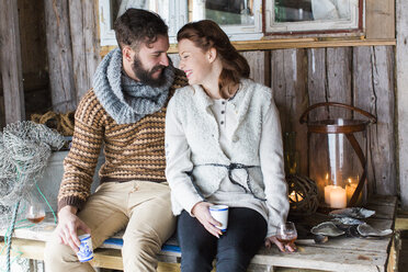 Young couple sitting on wooden table and talking - FOLF06155