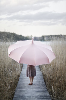 Frau mit Regenschirm auf einem Holzsteg stehend - FOLF06184