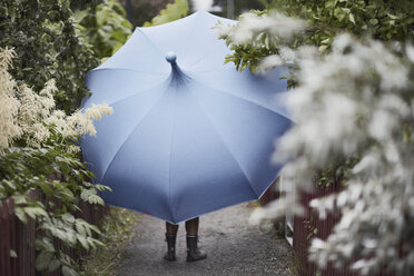 Frau mit Regenschirm geht im Garten spazieren - FOLF06186