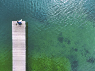 Germany, Bavaria, Chiemsee, man sitting on jetty - MMAF00336