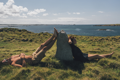 Frankreich, Bretagne, Landeda, Dunes de Sainte-Marguerite, junges Paar entspannt sich im Gras an der Küste, lizenzfreies Stockfoto
