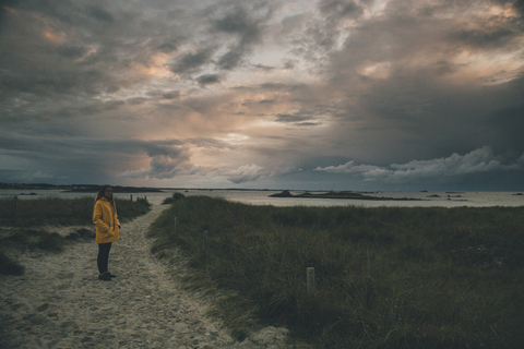 Frankreich, Bretagne, Landeda, Dünen von Sainte-Marguerite, junge Frau steht in der Düne in der Abenddämmerung, lizenzfreies Stockfoto